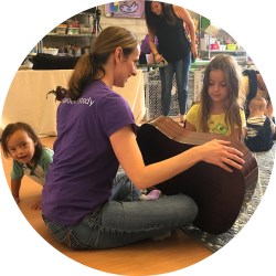 music teacher holding and playing a guitar in front of children