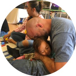 father kissing daughter on head during music class program