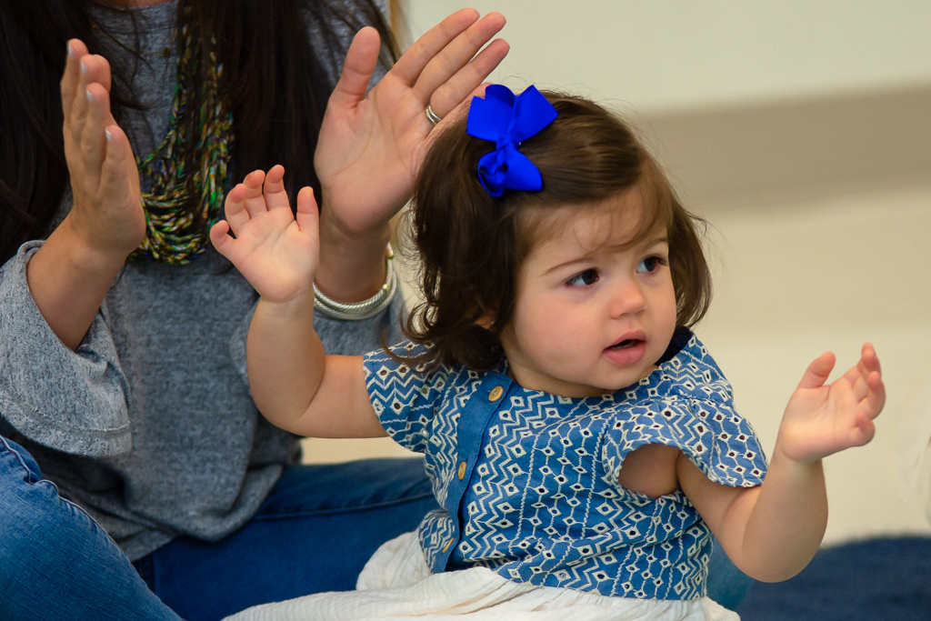 daughter with blue bow in music class clapping along with mother 