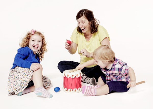 A mom plays instruments and sings with her children in a Music Together class.