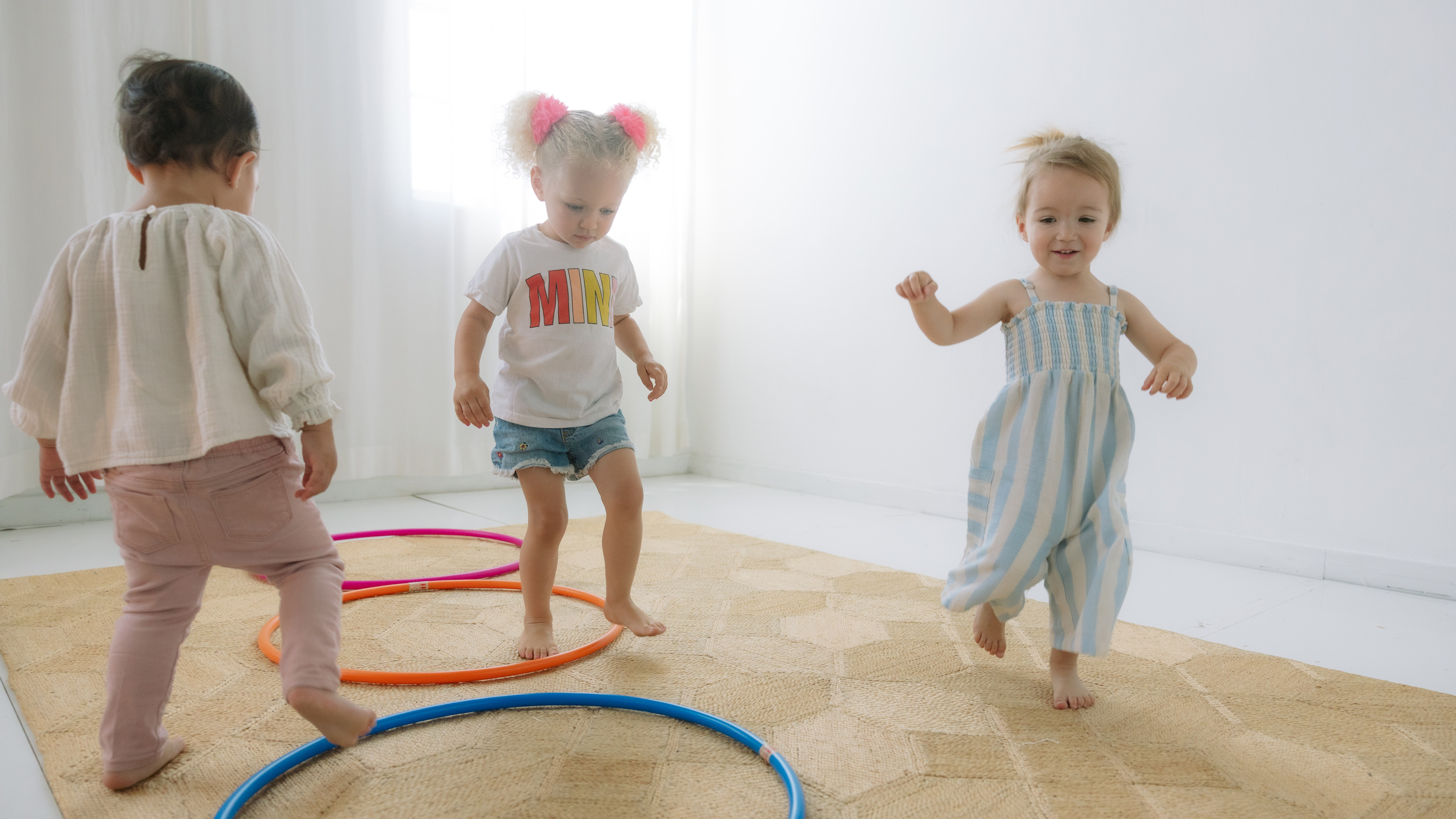 Three toddlers playing with colourful hula hoops in the In Harmony Music studio
