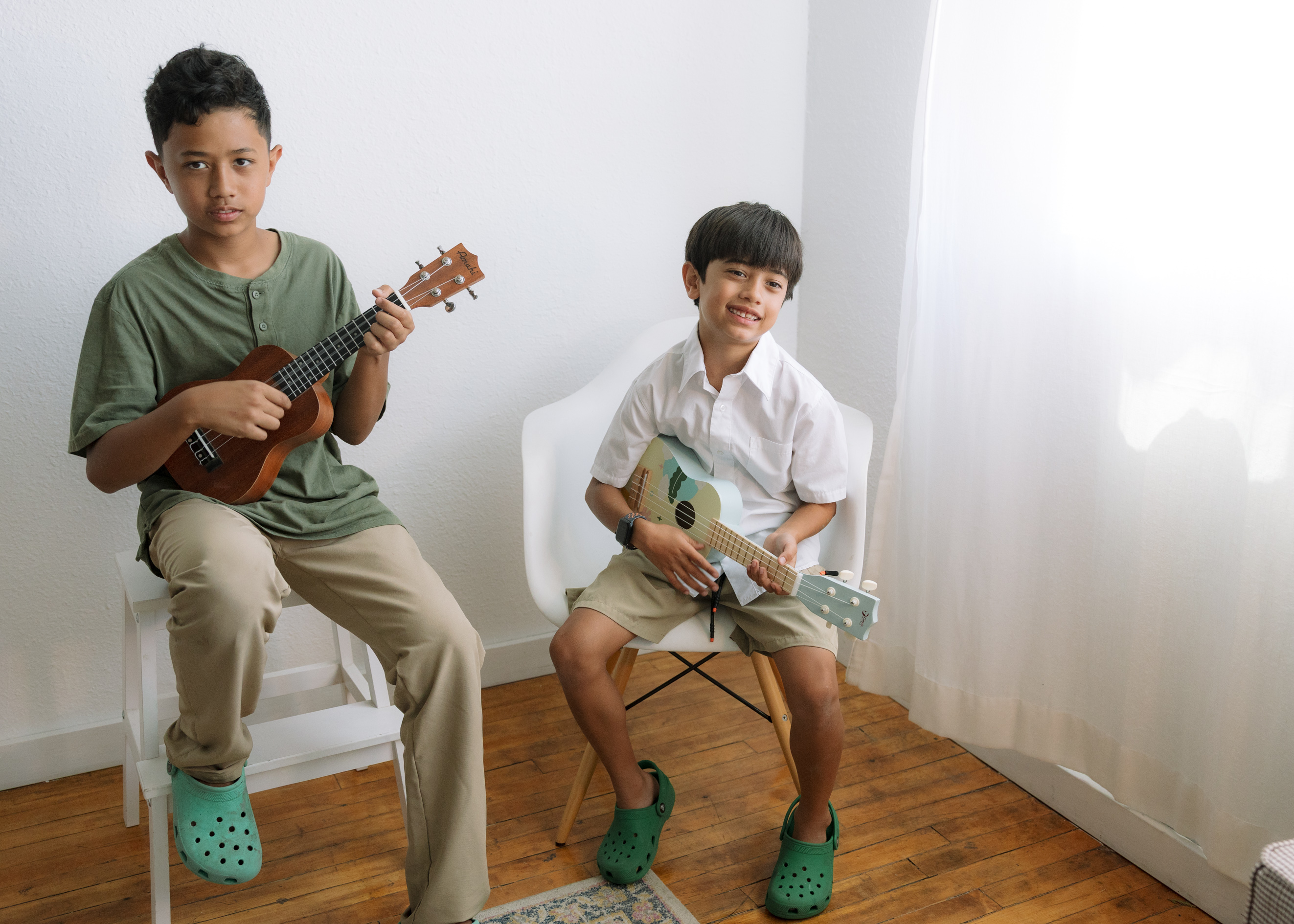 Older children strumming ukuleles and drumming in an In Harmony Music Strum, Drum and Sing class