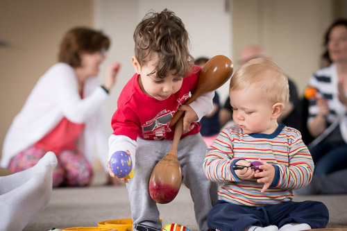 Baby and toddler playing instruments together in music class