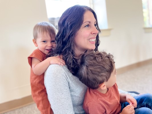 Mom enjoying snuggles from toddler and preschooler during music class