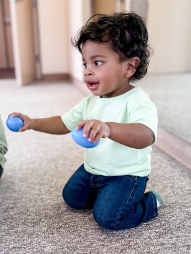 Baby, preschoolers, moms, and teacher drumming together in music class