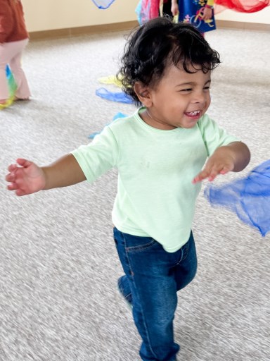Toddler delighting in dancing to the music with scarves