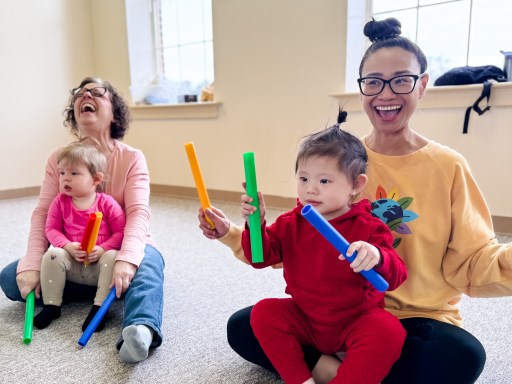Smiling mommy and preschooler playing with rhythm sticks in music class
