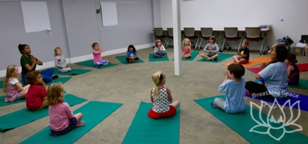 Children in a circle of yoga mats taking class in Elders Room (basement)