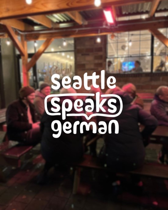 A cozy evening gathering at Good Society Brewery in West Seattle, with people seated at tables engaged in conversation. The Seattle Speaks German logo is overlaid on the blurred background showing the warm, welcoming atmosphere of the Monthly Feierabend German language meetup.